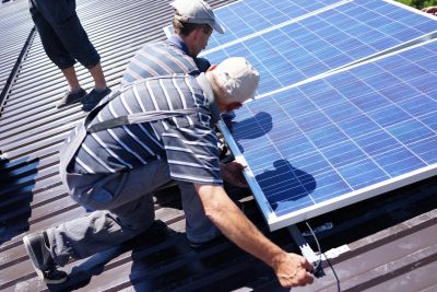 Man Installing Alternative Energy Photovoltaic Solar Panels On Roof SBI 300934036