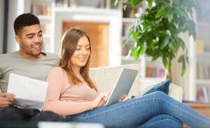 Photo of a couple on a couch looking at a computer and smiling.